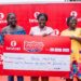 Maureen Bus-Moses (middle), a 2Moorch Money promo weekly prize winner, receives the cheque of GH₵20,000 with her mother and sister at the Takoradi Market Circle